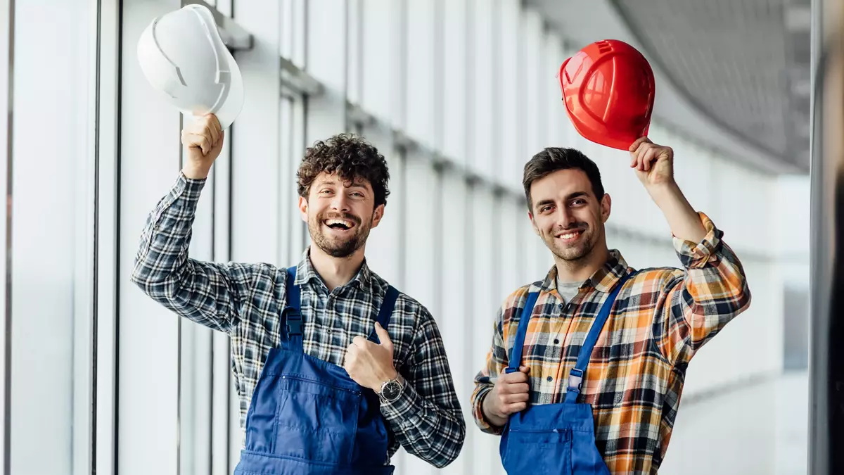 Trabajadores felices con casco en la mano