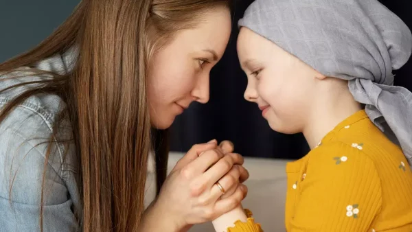 Madre agarrando las manos de su hija con cáncer