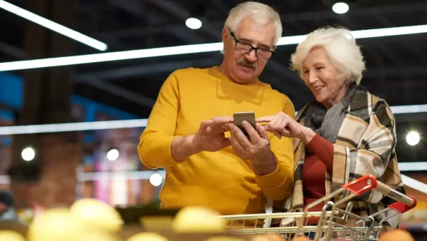 Jubilados comprando en el supermercado con el celular