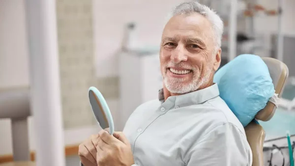 Hombre riendo en el dentista con su prótesis dental