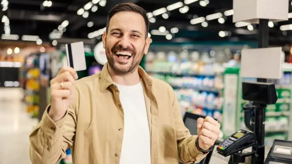 Hombre contento con su tarjeta en el supermercado