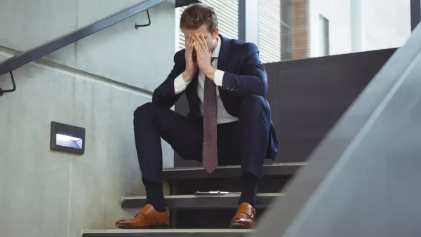 Trabajador con traje triste sentado en una escalera