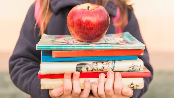 Estudiante con una manzana y sus libros