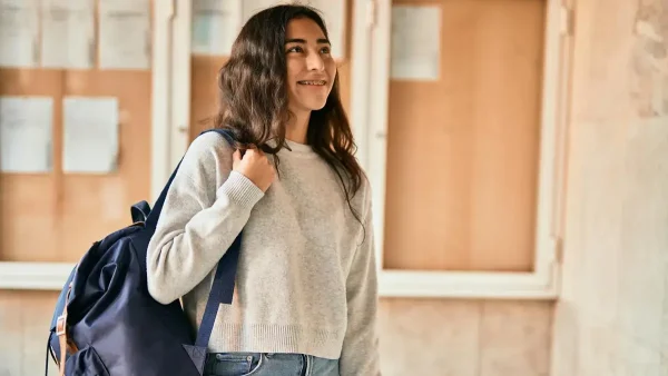 Estudiante riendo con su mochila en el hombro