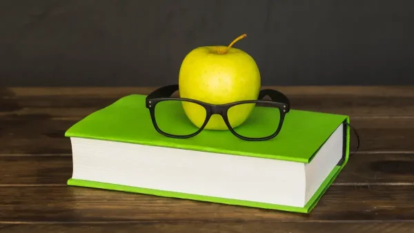 Libro de un estudiante con una manzana y un par de anteojos