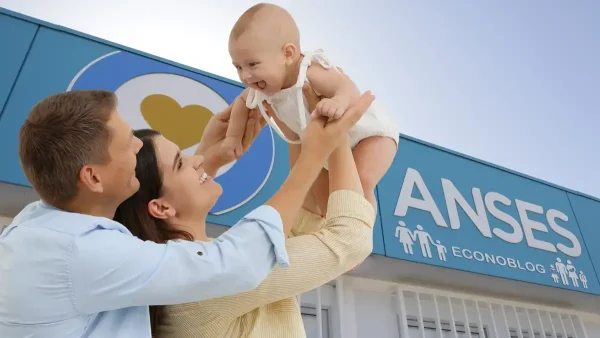 Familia con su bebé en Anses con un cartel del SUAF y AUH